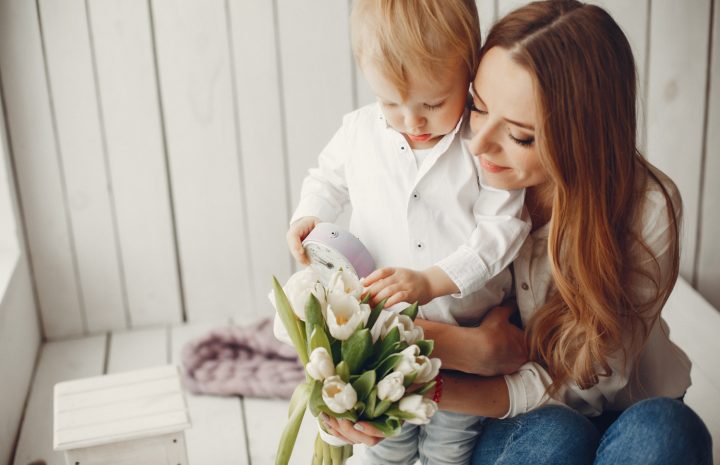 Une jeune maman et son petit garçon partagent un tendre moment autour d’un bouquet de tulipes blanches, dans une ambiance douce et lumineuse pleine de complicité.