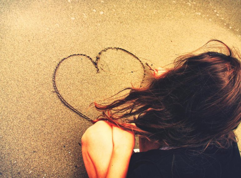 Une personne dessine un cœur dans le sable sur une plage, symbole d'amour, de tendresse et de souvenirs partagés. Cette image chaleureuse évoque les sentiments sincères, idéale pour accompagner un message d'amour, une pensée romantique, la Saint-Valentin ou une déclaration affectueuse.