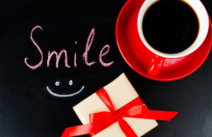 Une tasse de café rouge, un cadeau joliment emballé et le mot « Smile » accompagné d’un visage souriant composent une image joyeuse et positive. Cette scène évoque la bonne humeur, les petites attentions et les plaisirs simples du quotidien. Une illustration idéale pour célébrer la Journée mondiale du sourire, partager une pensée positive ou simplement donner le sourire à une personne chère.