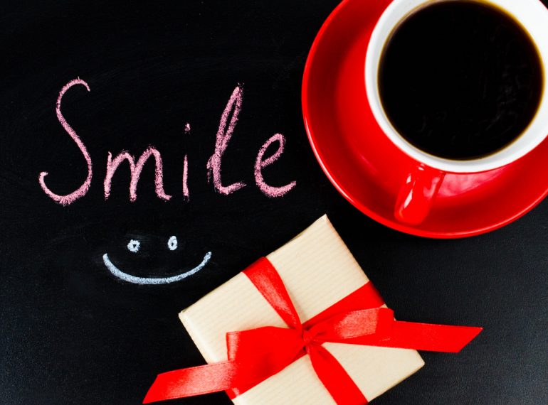 Une tasse de café rouge, un cadeau joliment emballé et le mot « Smile » accompagné d’un visage souriant composent une image joyeuse et positive. Cette scène évoque la bonne humeur, les petites attentions et les plaisirs simples du quotidien. Une illustration idéale pour célébrer la Journée mondiale du sourire, partager une pensée positive ou simplement donner le sourire à une personne chère.